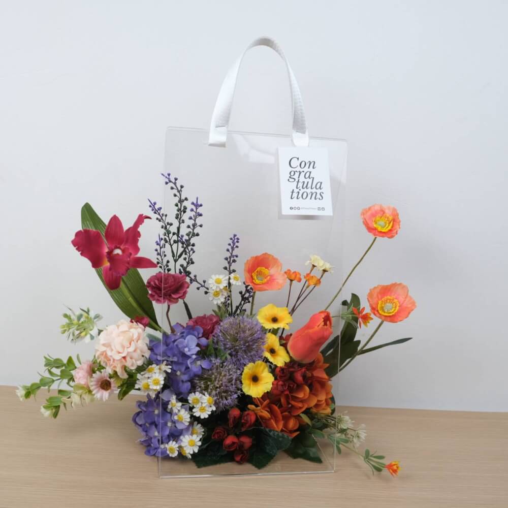 ดอกไม้ประดิษฐ์ผ้าในแจกัน  JGLORYFLOWER  แจกันพลาสติกใส รูปทรงกระเป๋า ดอกไม้คละชนิด สีม่วง/ส้ม
