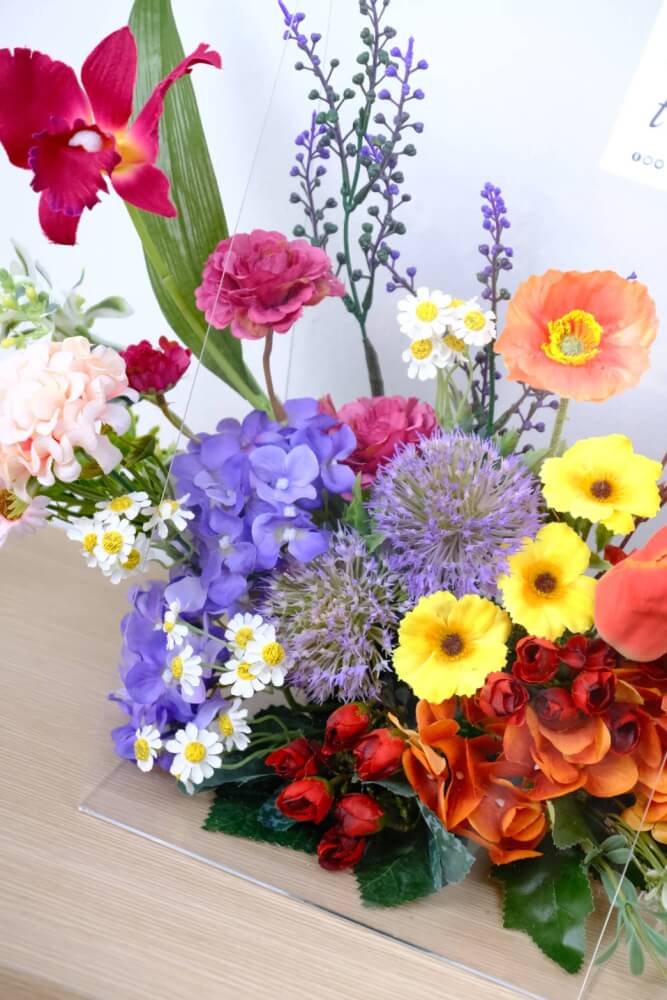 ดอกไม้ประดิษฐ์ผ้าในแจกัน  JGLORYFLOWER  แจกันพลาสติกใส รูปทรงกระเป๋า ดอกไม้คละชนิด สีม่วง/ส้ม