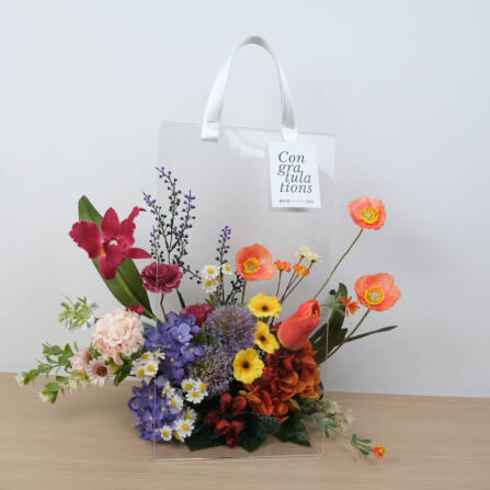 ดอกไม้ประดิษฐ์ผ้าในแจกัน  JGLORYFLOWER  แจกันพลาสติกใส รูปทรงกระเป๋า ดอกไม้คละชนิด สีม่วง/ส้ม_1